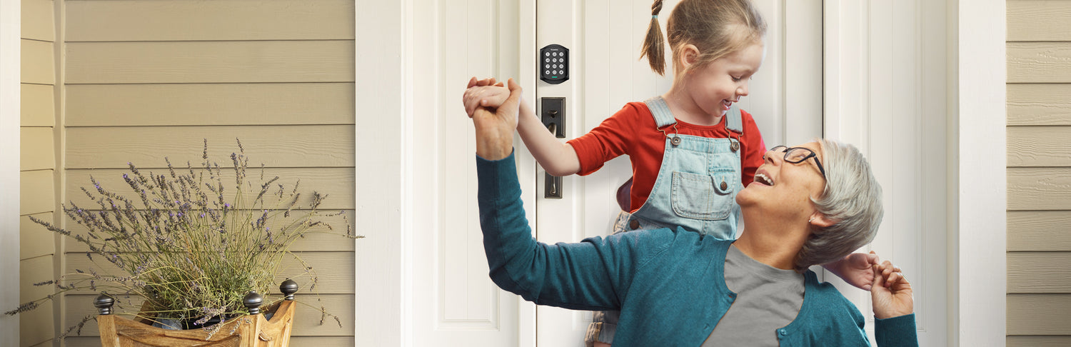 Grandparent and kid in front of a white door with KA200 Z-Wave smart lock